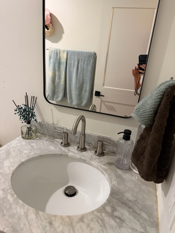 Clean marble bathroom vanity after professional deep cleaning with styled towels and reed diffuser